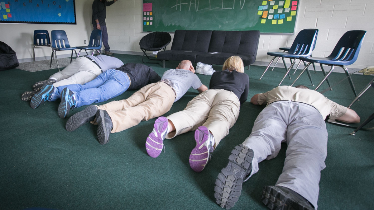 School employees play dead on the floor during an active shooter mock scenario.