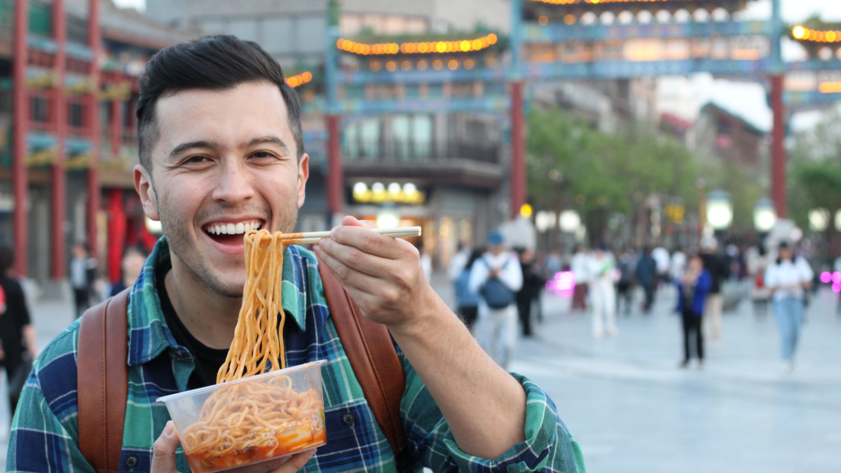 Delighted man eating Asian food outdoors