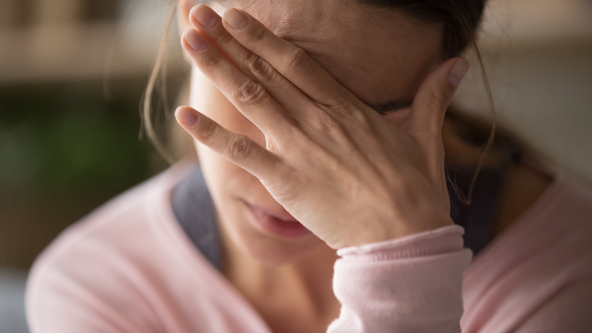 Sad tired young woman touching forehead having headache migraine or depression, upset frustrated girl troubled with problem feel stressed cover crying face with hand suffer from grief sorrow concept