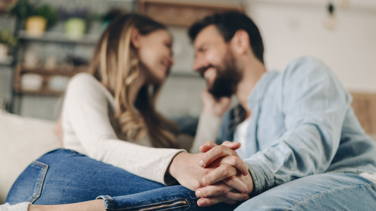 Close up of a couple in love flirting at home and holding hands.
