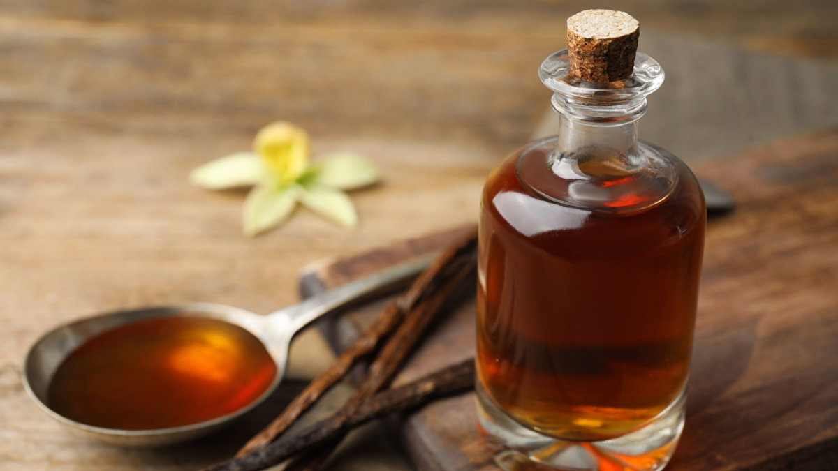 Aromatic homemade vanilla extract on wooden table, closeup.