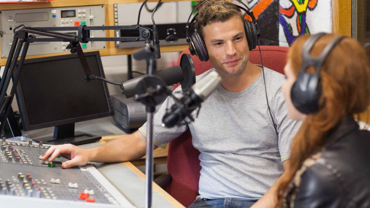 Attractive content radio host interviewing a guest in studio at college