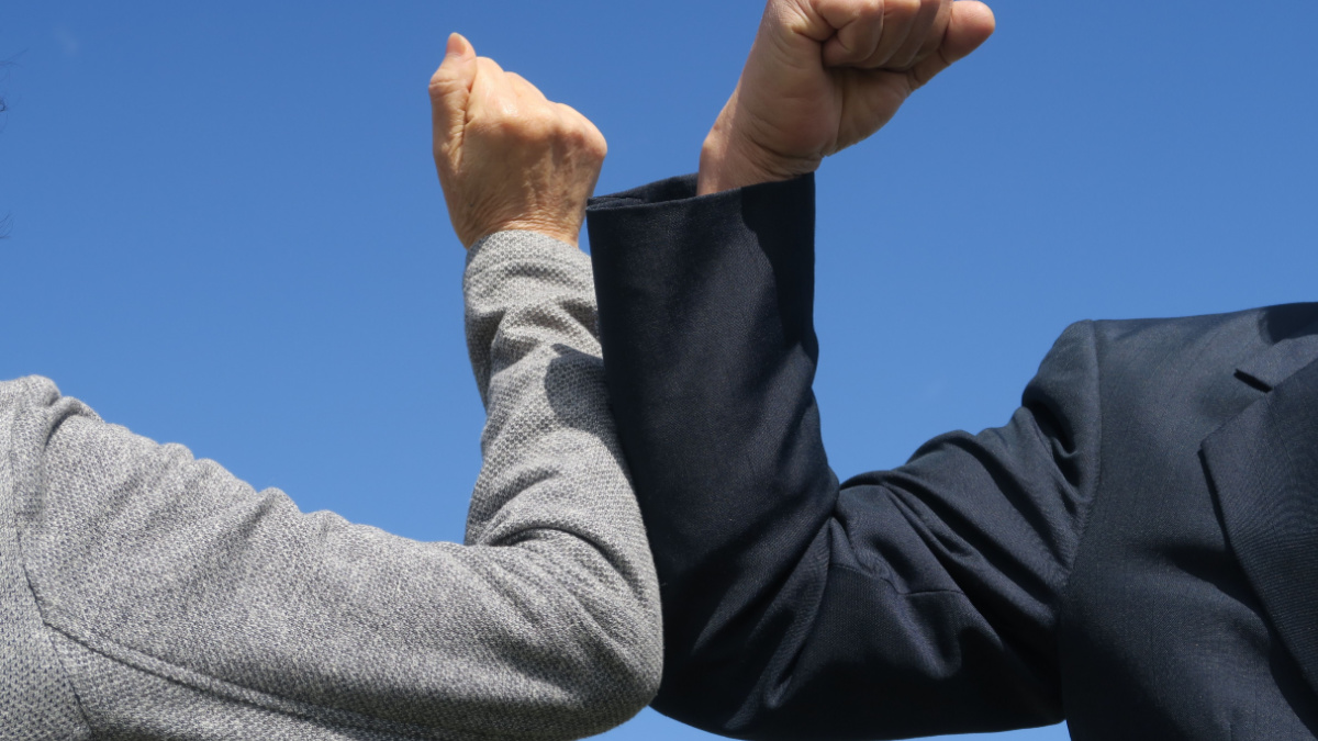 Elbow bumping. A new way of greeting to avoid the spread of coronavirus (COVID-19). Two people (a man and a woman) bump elbows instead of hug or handshake. New normal.