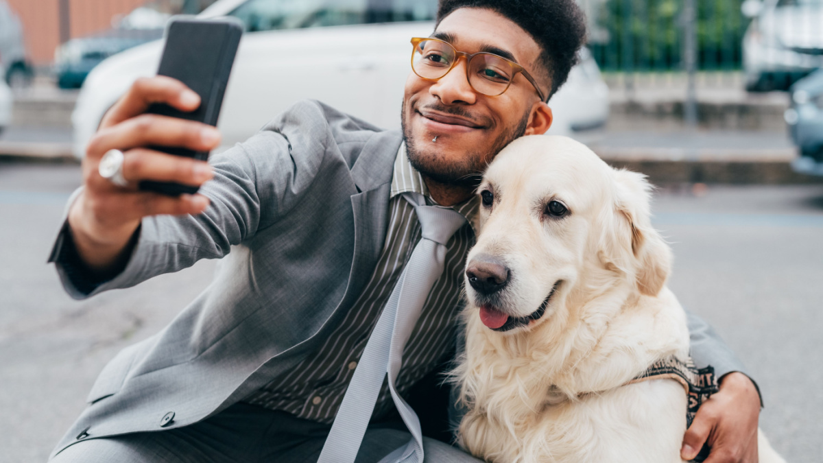 Young beautiful mixed race business man taking selfie with his dog - best friends, bonding, sociable concept