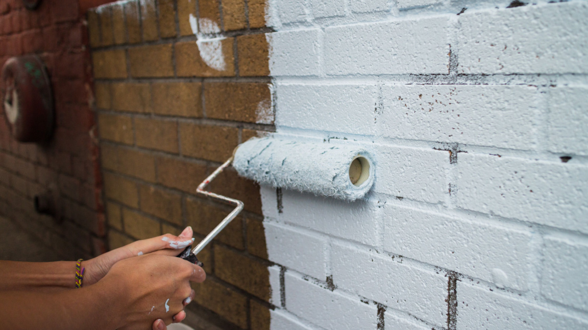 painting on a fresh coat on brick wall