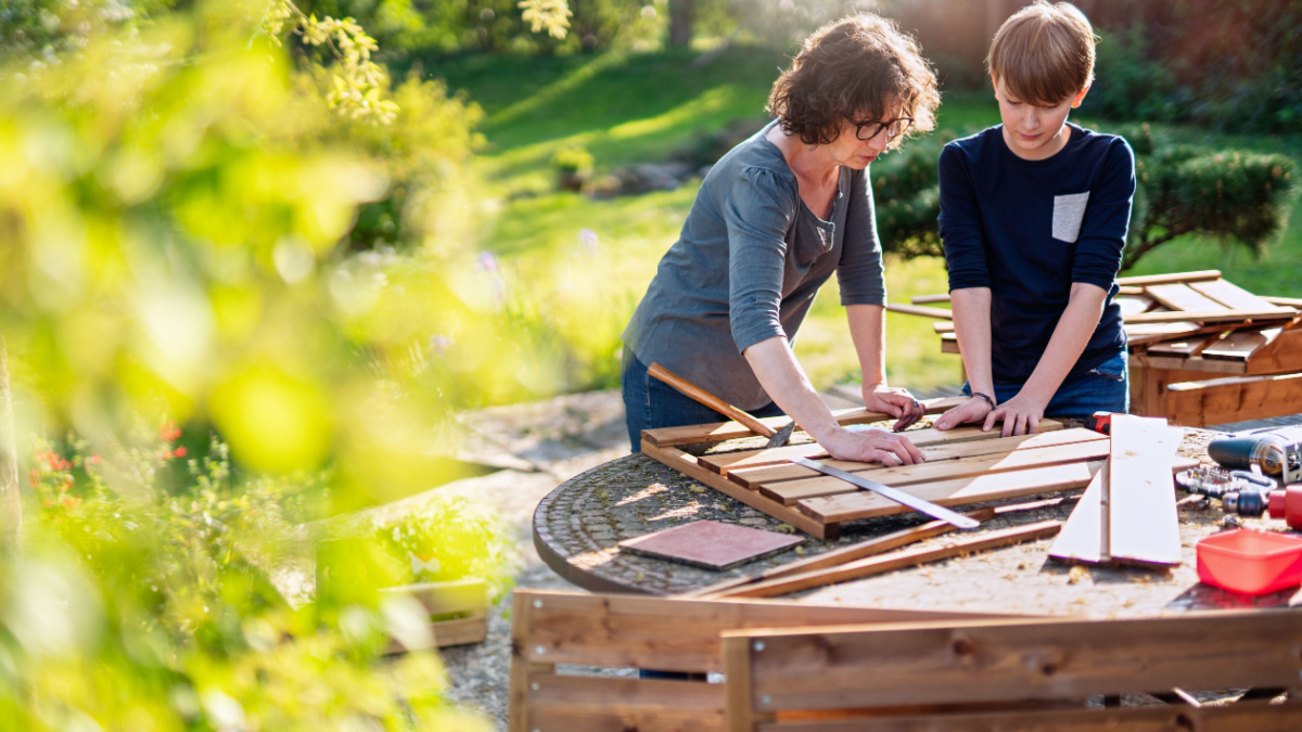 A mother and her son build wooden planters to grow organic vegetables on the terrace