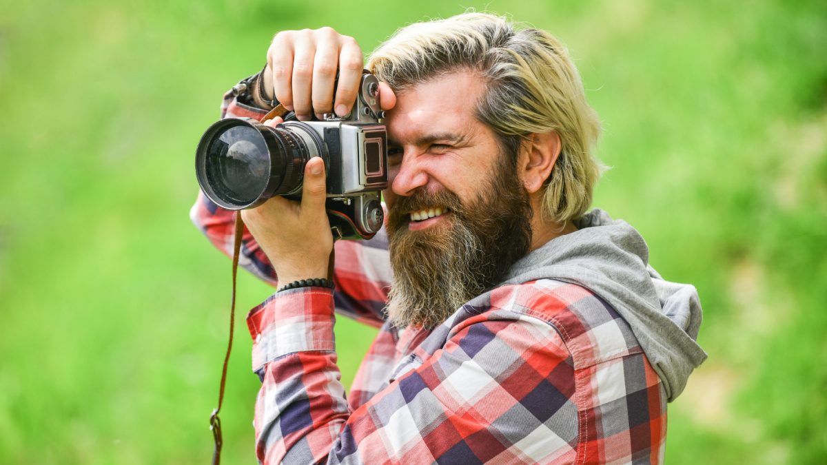Enjoying hot day. bearded man hipster take photo. photo shooting outdoor. brutal man traveler with retro camera. photography in modern life. travel tips. professional photographer use vintage camera.
