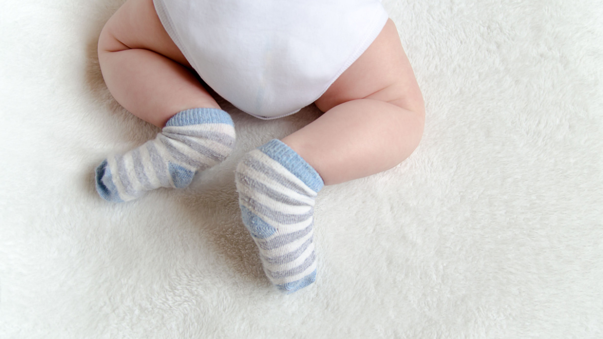 newborn baby sleeping on white. rear view. butt in a diaper, with a adorable crossed legs and feet