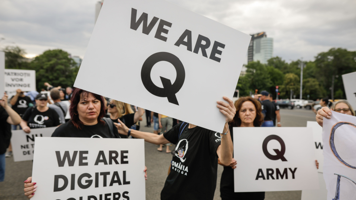 People display Qanon messages on cardboards during a political rally.