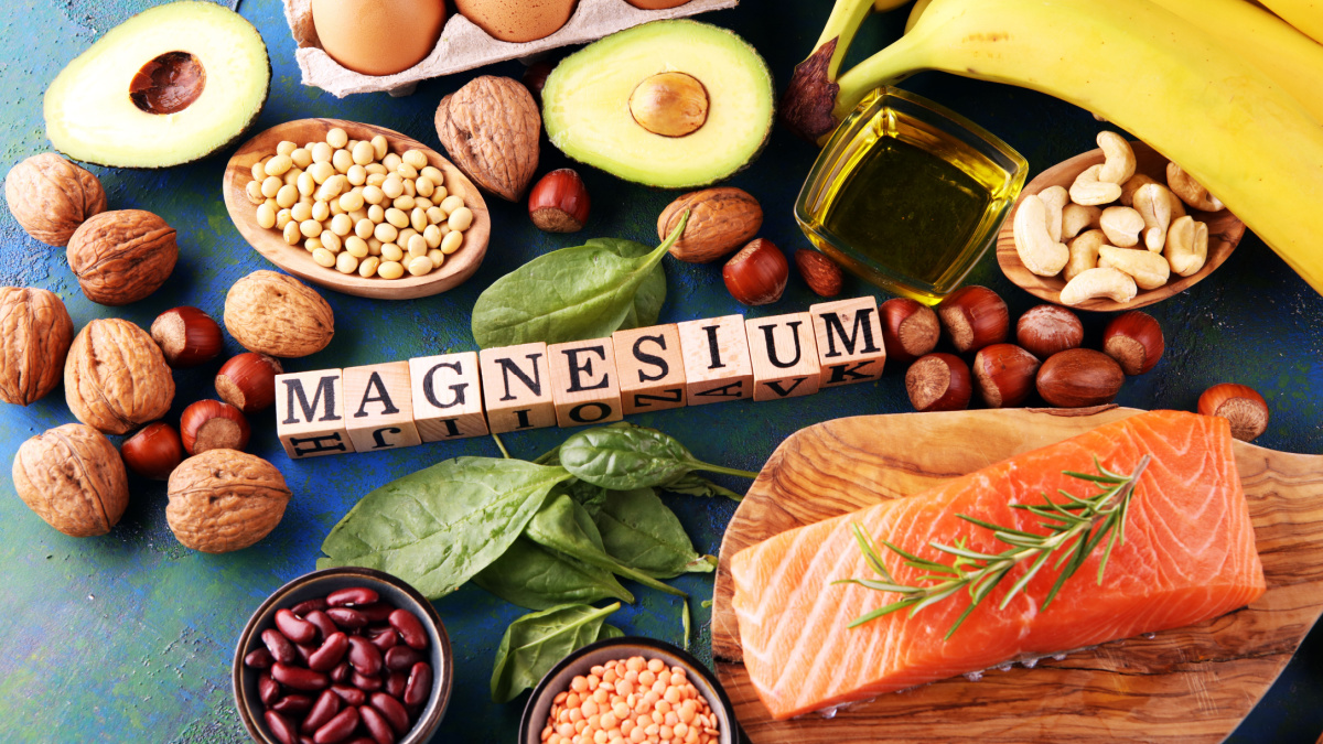 Products containing magnesium: bananas, almonds, avocado, nuts and spinach and eggs on table