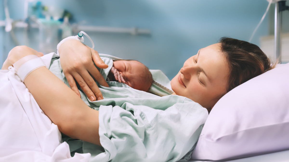 Mother and newborn. Child birth in maternity hospital. Young mom hugging her newborn baby after delivery. Woman giving birth. First moments of baby life after labor.
