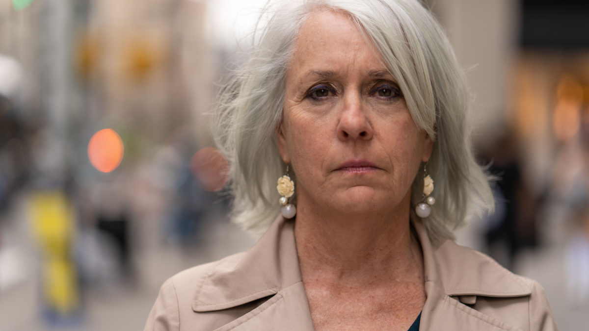 Mature caucasian woman in city serious face portrait on a street.