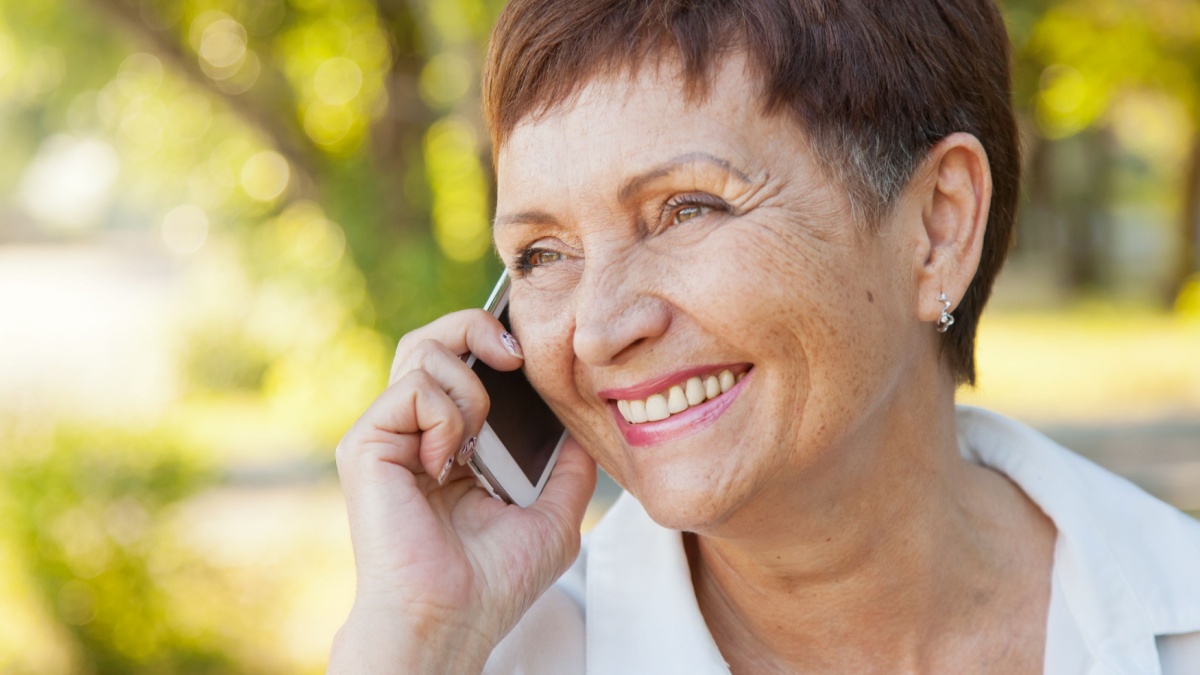 beautiful woman of 50 years with a mobile phone outdoors.