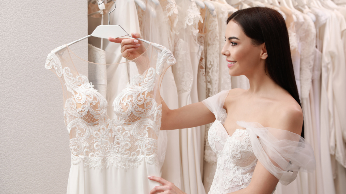Young woman choosing wedding dress in salon
