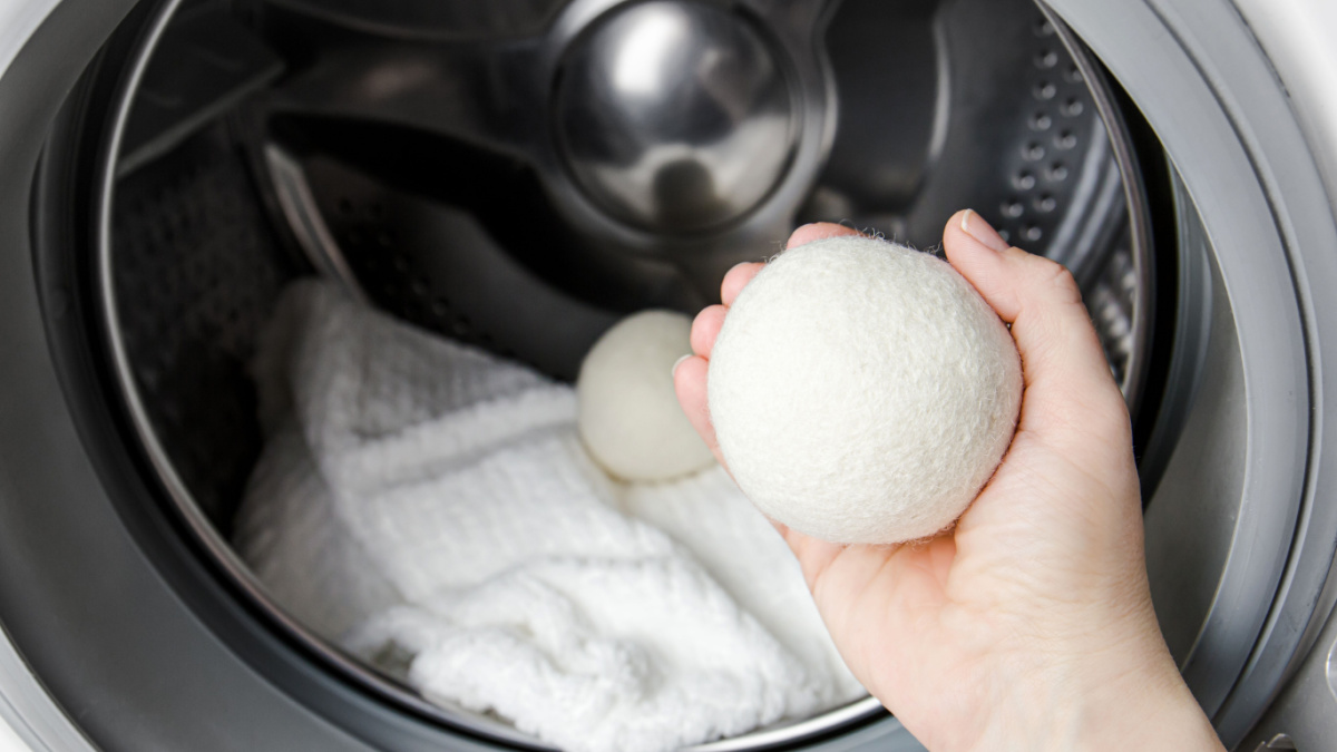 8 Ways Frugal Homeowners Can Save Money on Their Energy Bill 9 Woman using wool dryer balls for more soft clothes while tumble drying in washing machine concept. Discharge static electricity and shorten drying time, save energy.