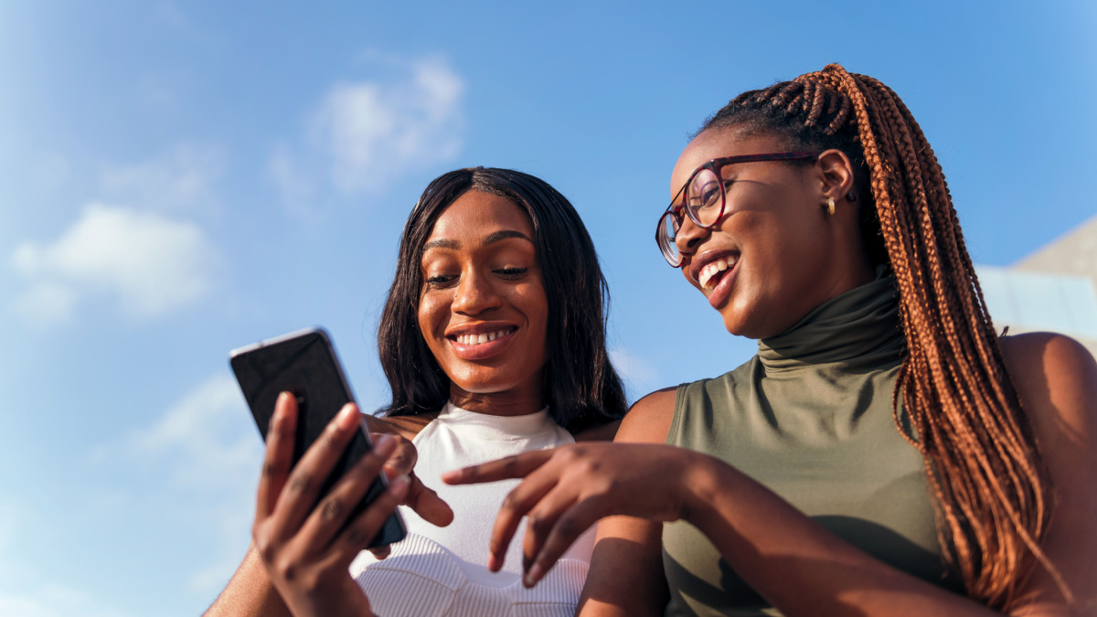 two young african women having fun looking at the cell phone, concept of youth and communication technology.