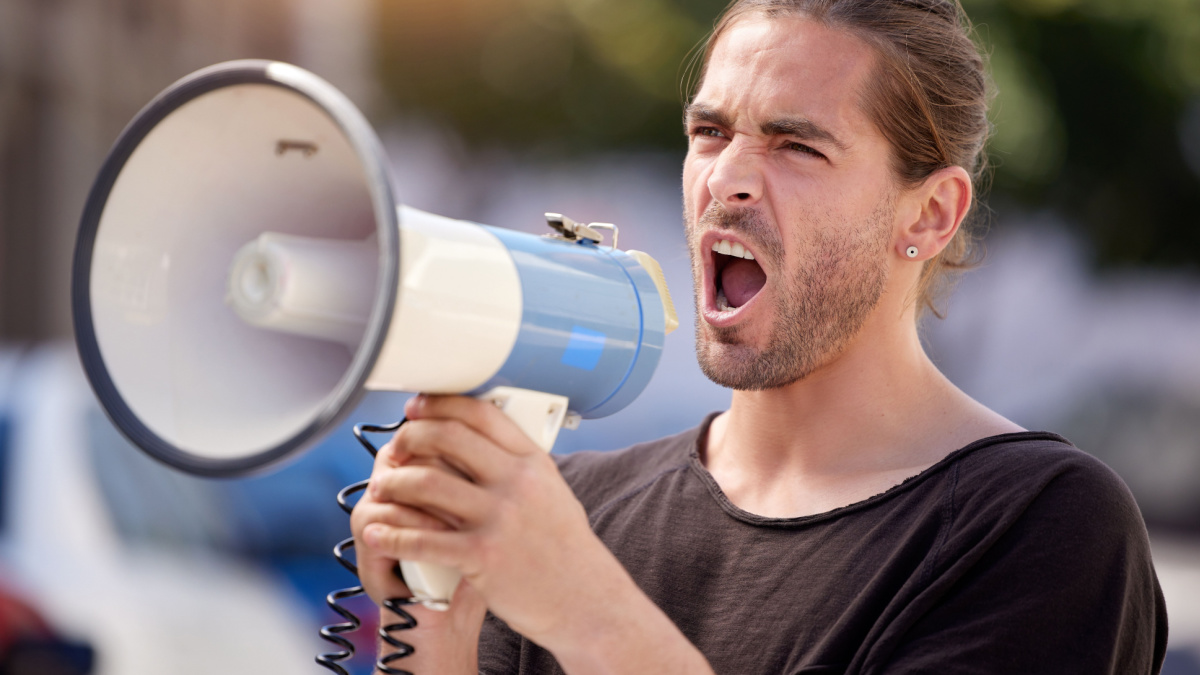 Working toward my goal. Shot of a young man using a megaphone at a protest rally.