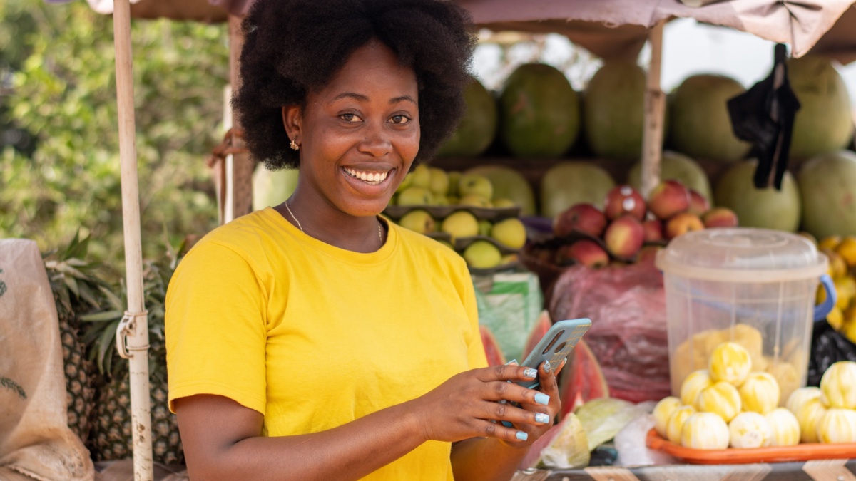 african market woman using her phone smiling.