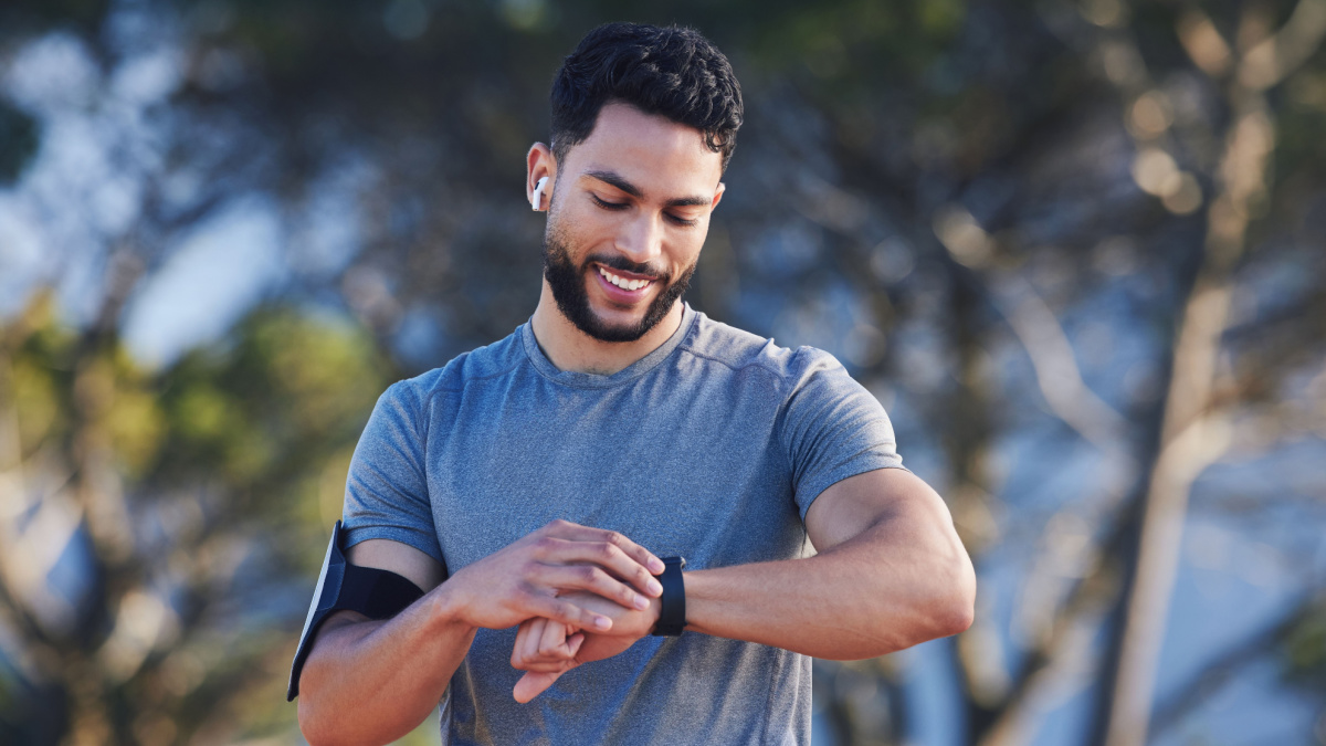 Runner with fitness smart watch, app and check running time for health tracking tech on nature run.
