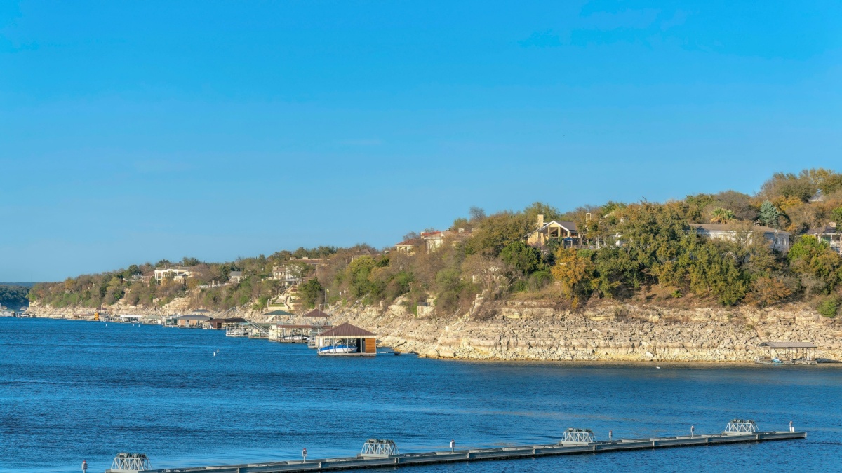 Lake Austin, Austin, Texas- Docks at the front of the rich neighborhood on top of the slope. There are large residential buildings on top with docks near the shore.