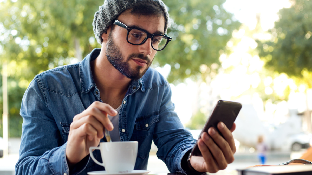 Outdoor portrait of modern young man with mobile phone in the street.