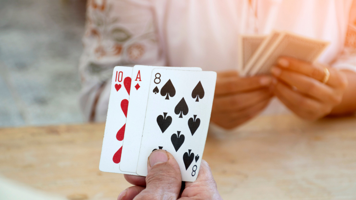 Closeup hands holding cards of retired people who playing card in a retirement home, happiness of elderly people after retirement by playing card.