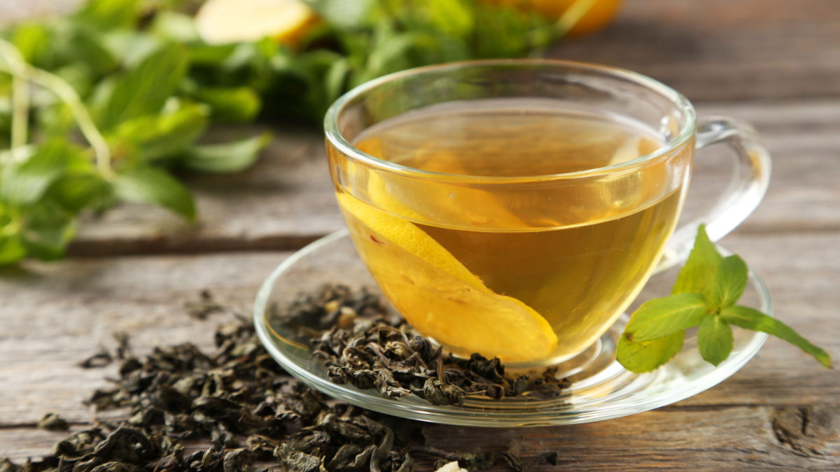 Cup with green tea on grey wooden background