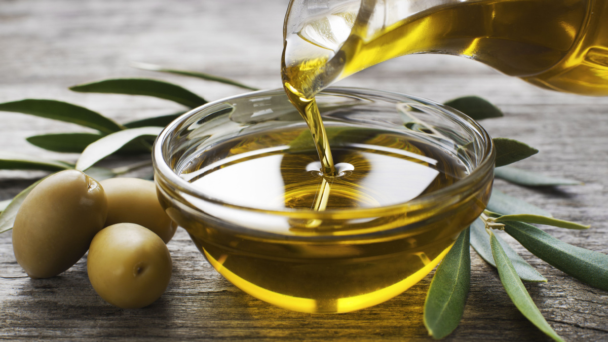 Bottle pouring virgin olive oil in a bowl close up