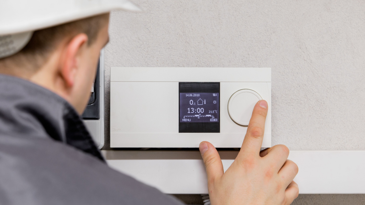 Engineer adjusting thermostat for efficient automated heating system