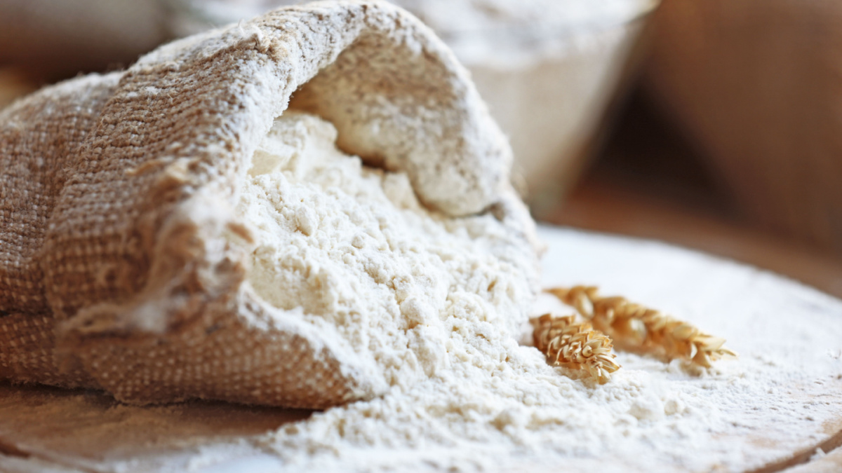 Flour in burlap bag on cutting board and wooden table background