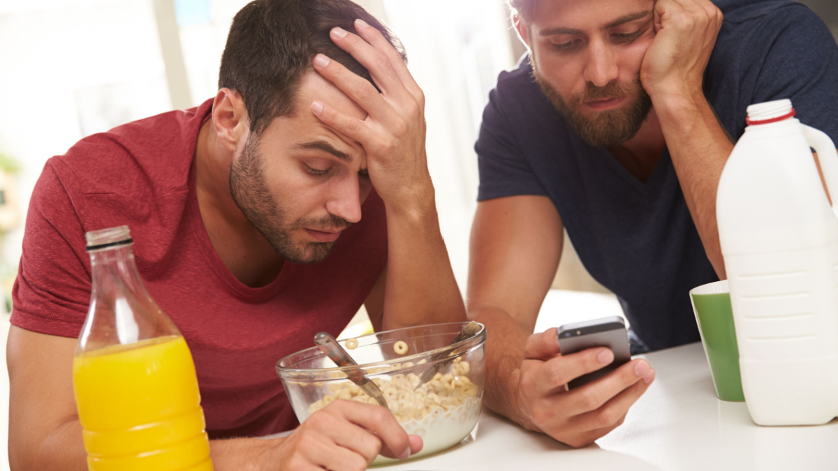 Male Friends Checking Phones After Sending Text Whilst Drunk