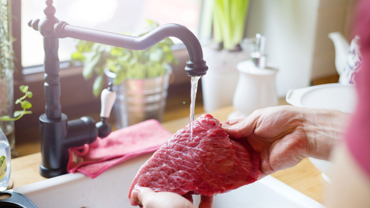 Unrecognizable man in the kitchen preparing beef steak