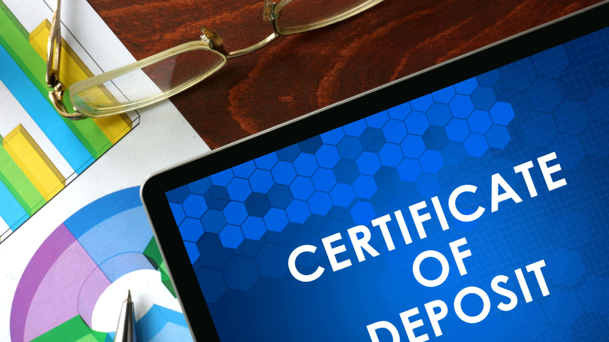 Tablet with certificate of deposit (CD) on a table. Business concept.