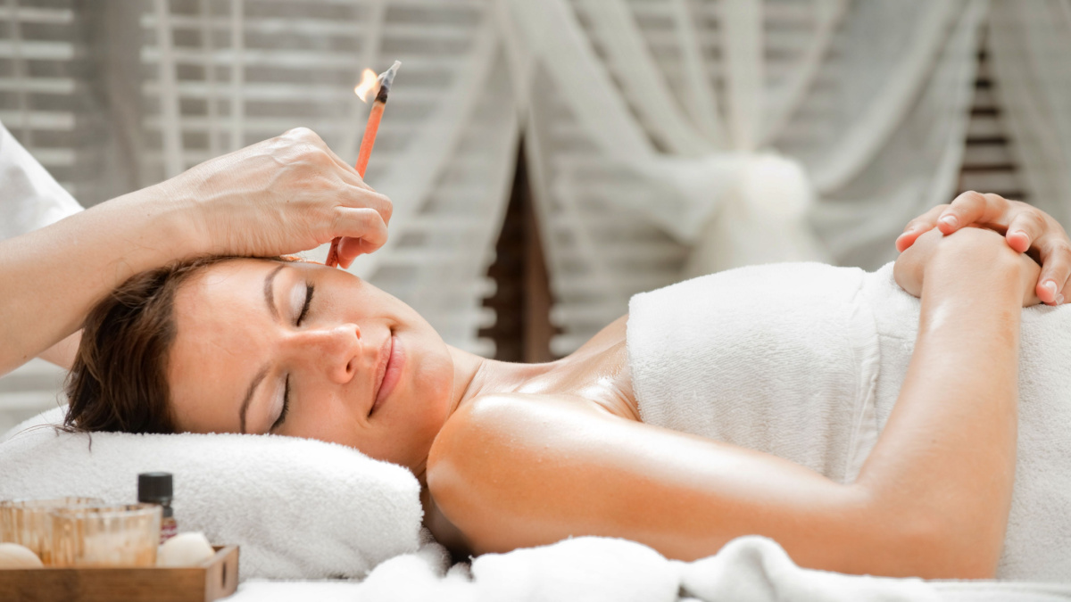 Ear candling being carried out on an attractive caucasian woman in a spa