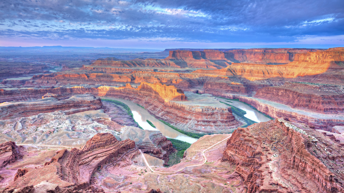 Sunrise illuminates clouds and the canyon walls of this colorful sunrise scene from Deadhorse Point. Deadhorse Point State Park is adjacent to Canyonlands National Park and near Moab, Utah.