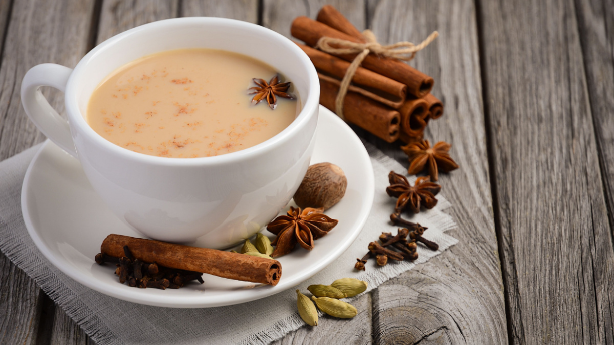 Indian masala chai tea. Masala chai spiced tea with milk and spices on rustic wooden table