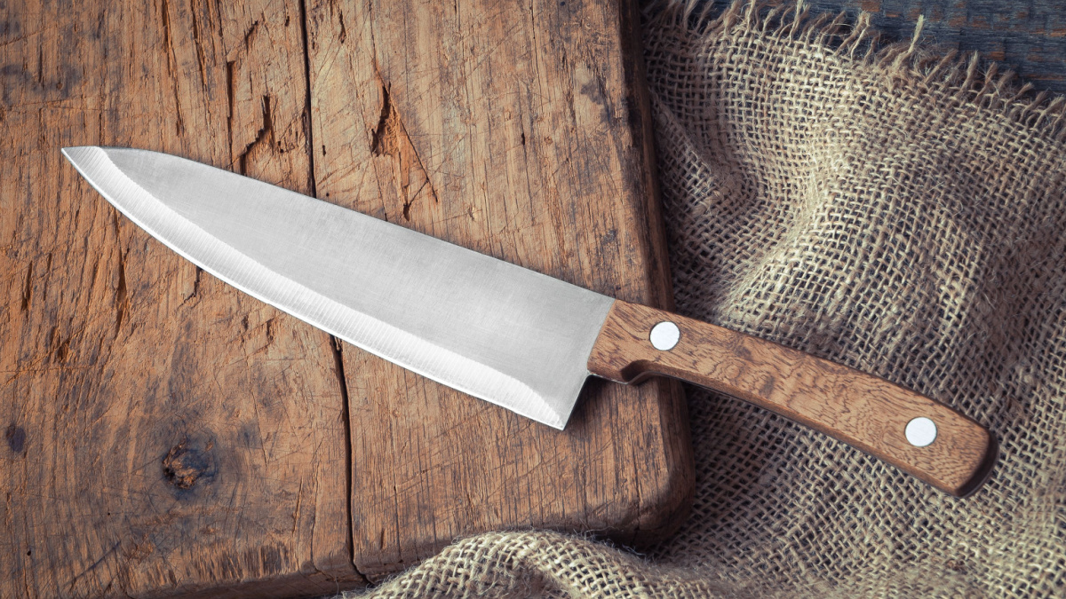 Big kitchen knife lying on an old cutting board