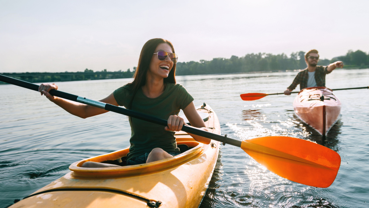 Couple kayaking together. Beautiful young couple kayaking on lake together and smiling