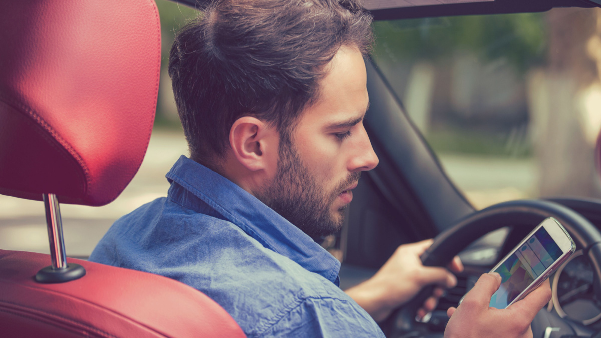 Man using cell phone texting while driving. Risky, reckless driver concept.