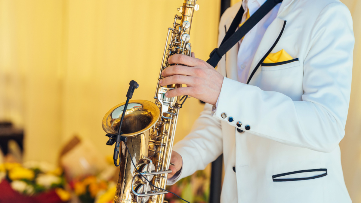 Saxophonist in white jacket plays the saxophone. Saxophonist jazz man with saxophone on wedding party