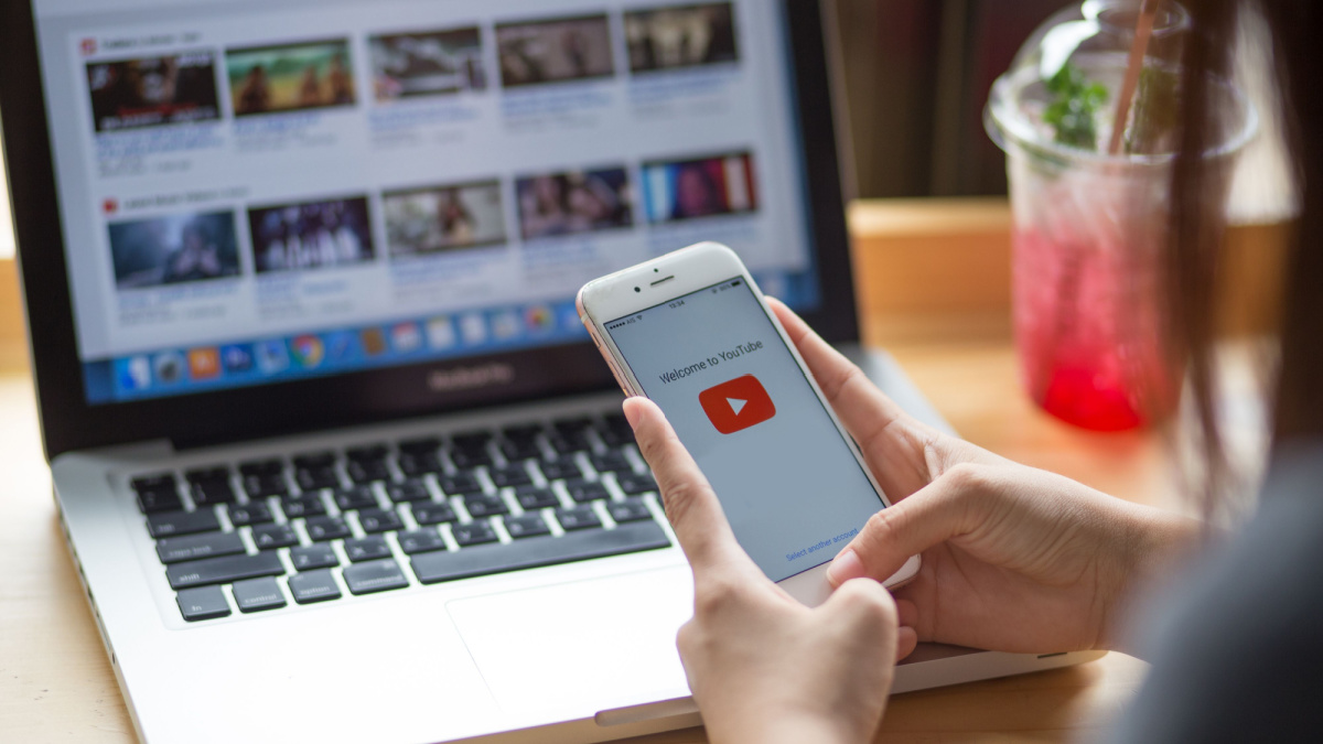 Woman holding iPhone with video service YouTube on the screen. iPhone was created and developed by the Apple inc.