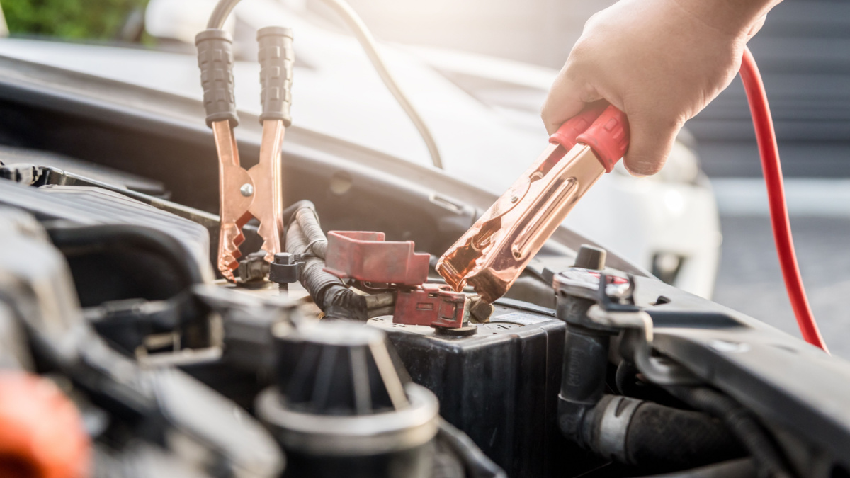 Close up of hand Charging car battery with electricity trough jumper cables