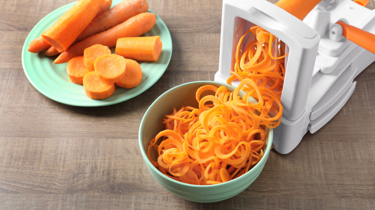Spiral vegetable slicer with carrot spaghetti on table