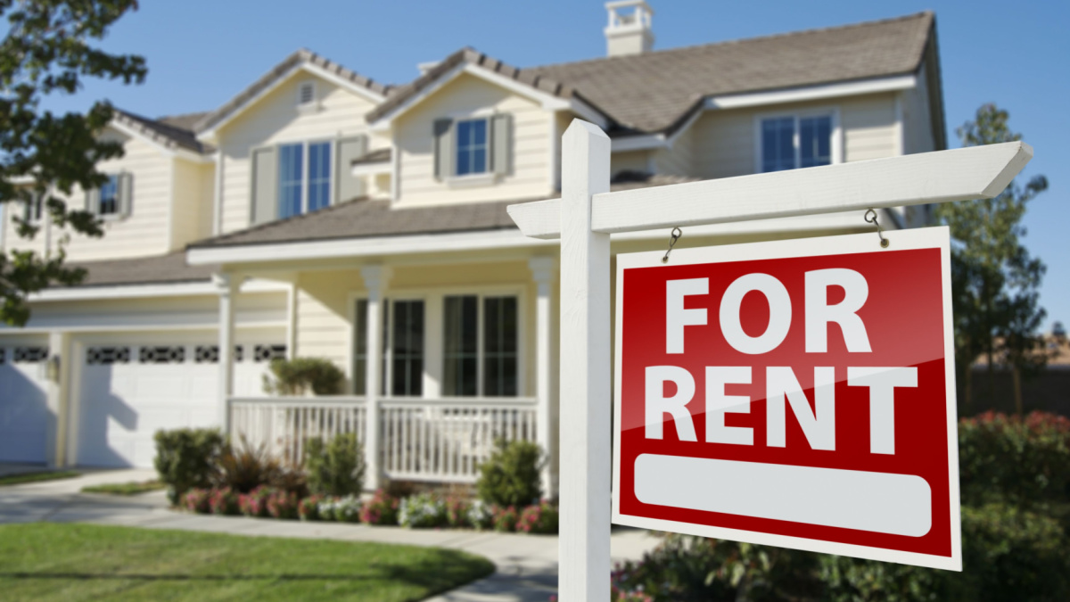 Left Facing Red For Rent Real Estate Sign in Front of Beautiful House.