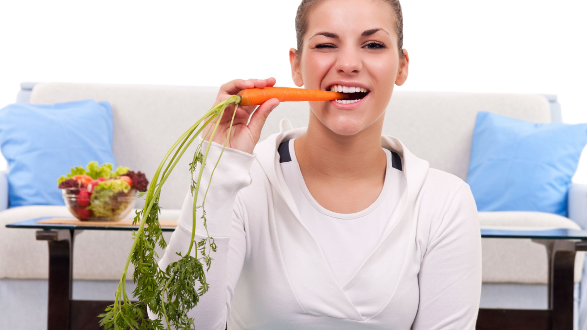 healthy young woman eating a carrot-close up