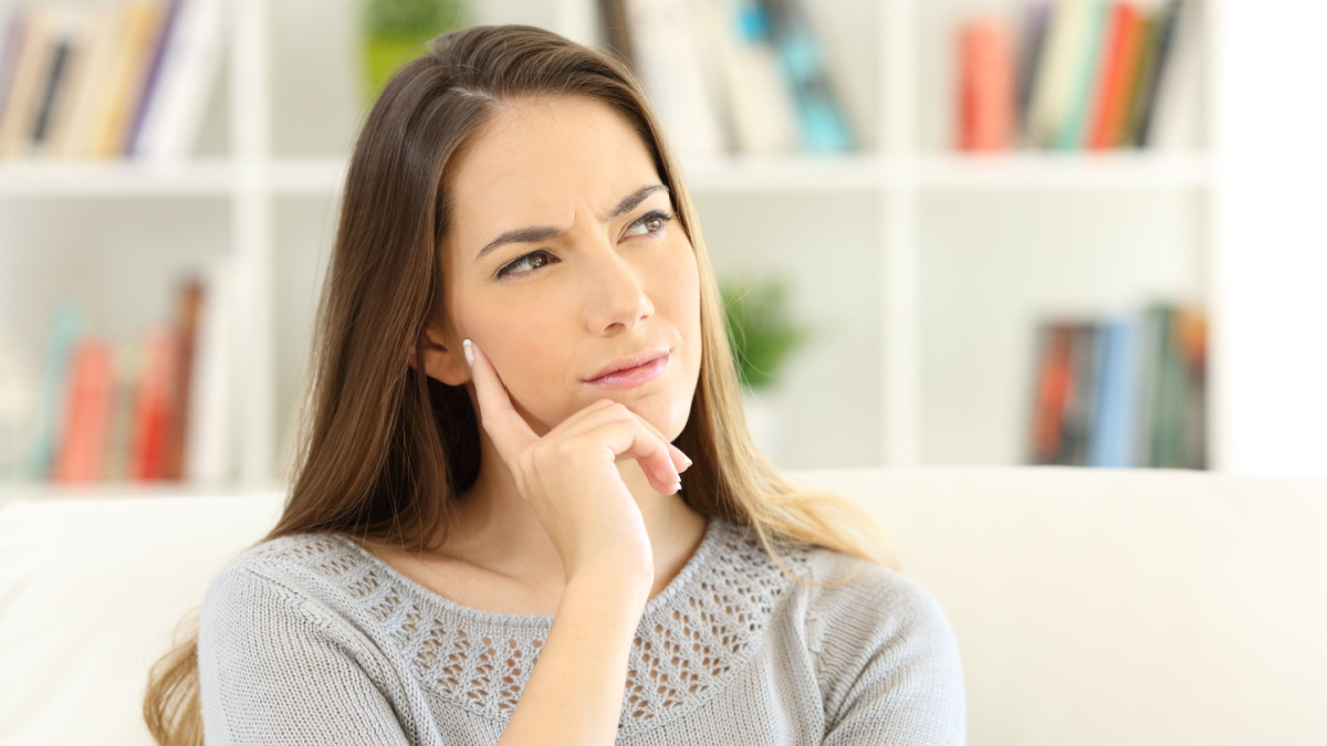 Front view portrait of a woman wondering sitting on a sofa at home