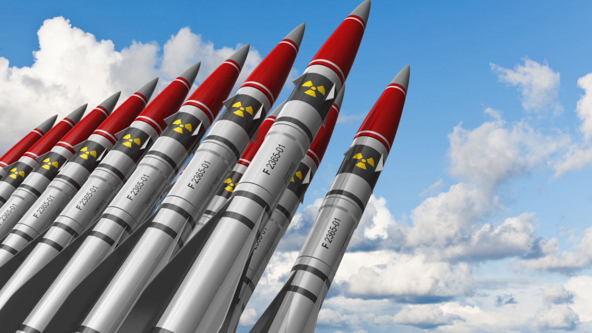 Row of heavy nuclear missiles against blue sky with clouds