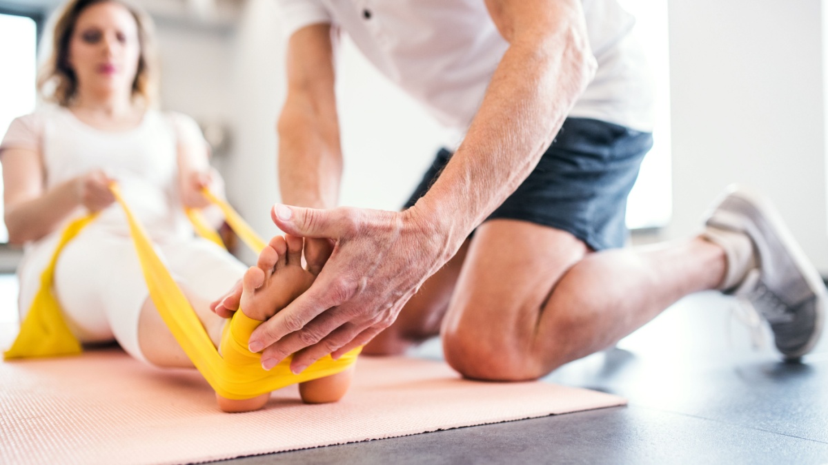 Unrecognizable senior physiotherapist working with a female patient.