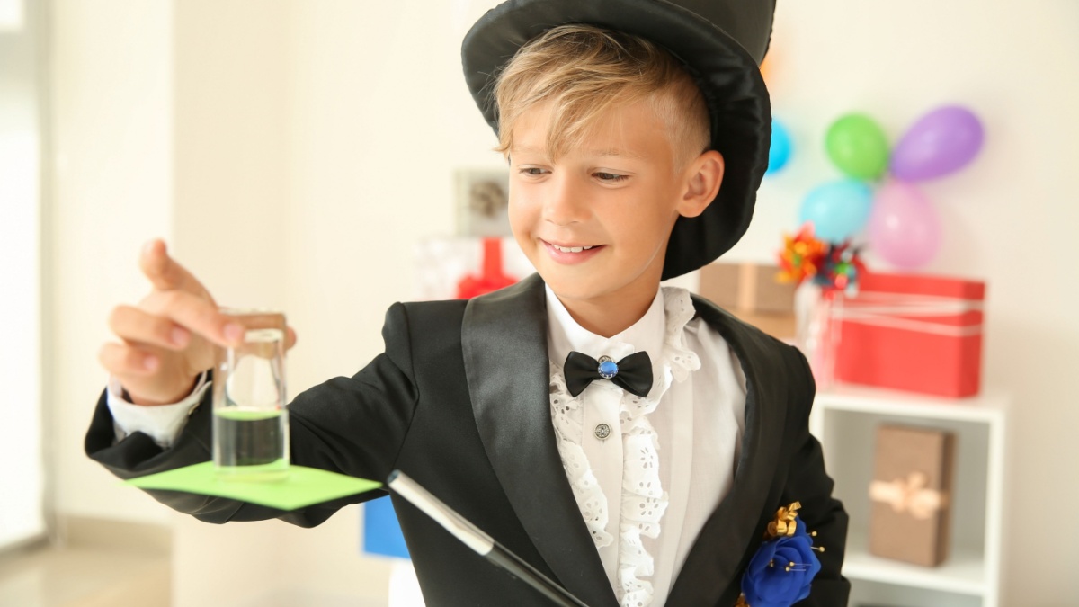 Cute little magician showing trick indoors