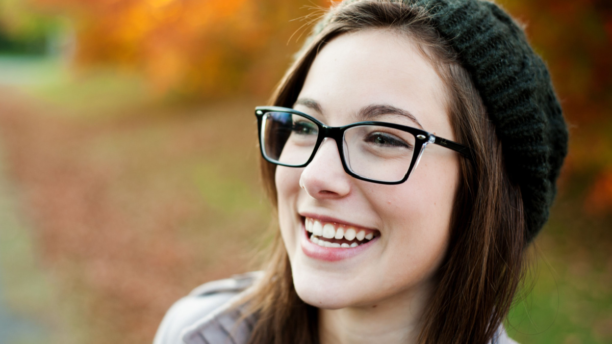 Young woman wearing glasses laughing in the fall.